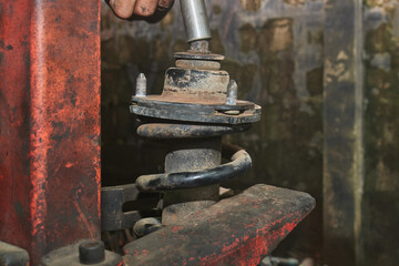 Car Mechanic or Auto Mechanic Loosen Upper Shock Absorber Nut by Wind Block. Shock Absorber Removal by Spring Compressor Tool