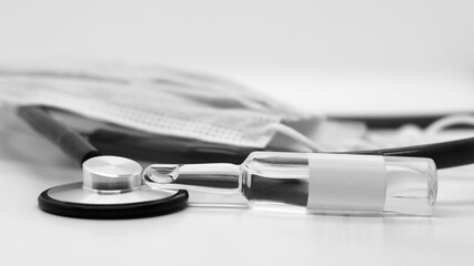 Stethoscope, glass ampoules and medical mask, black and white image