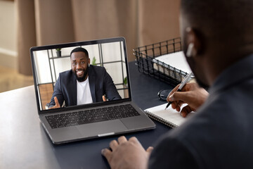 Happy young African American talking chat with to his coworker using laptop. Video call, self-isolation concept - obrazy, fototapety, plakaty