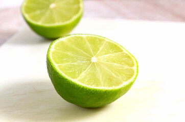 Cut off half of a green lime on a light background.