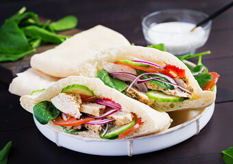 Pita stuffed with chicken, tomato, cucumber and spinach on wooden background. Middle Eastern cuisine.