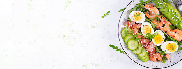 Ketogenic diet breakfast. Salt salmon salad with boiled shrimps, prawns, cucumbers, arugula, eggs and avocado. Keto, paleo lunch. Top view, overhead