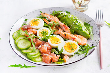 Fototapeta na wymiar Ketogenic diet breakfast. Salt salmon salad with boiled shrimps, prawns, cucumbers, arugula, eggs and avocado. Keto, paleo lunch.