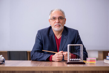 Old teacher physicist sitting in the classroom