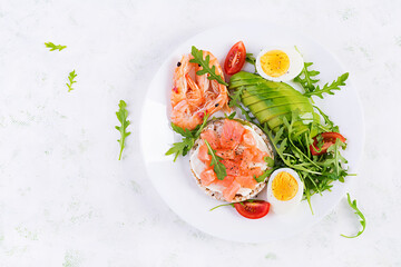 Ketogenic diet breakfast. Salt salmon salad with boiled shrimps, prawns, tomatoes, arugula, eggs and avocado. Keto, paleo lunch. Top view, overhead