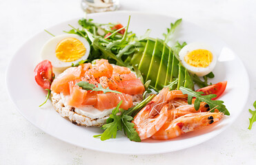 Ketogenic diet breakfast. Salt salmon salad with boiled shrimps, prawns, tomatoes, arugula, eggs and avocado. Keto, paleo lunch.
