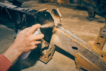 Car Mechanic or Auto Mechanic Spray Black Paint Side of Car Chassis in Garage in Vintage Tone