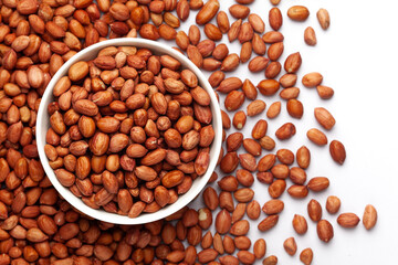 Close-up of organic red brown peanuts (Arachis hypogaea) in white Ceramic bowl with the gradient background of peanuts . Top view
