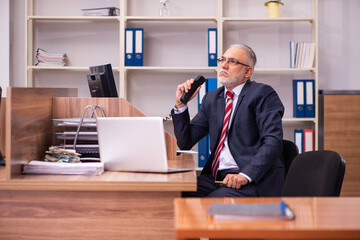 Old male employee sitting in the office