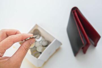 saving your money concept - woman put coin from wallet in a box for economical lives