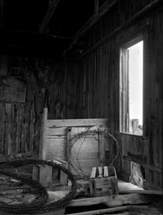 JJ Building Interior. A rustic black and white still life of the interior of and abandoned farm building with spools of barbed wire propped against the wall. Near New Boston, Missouri USA, 1980