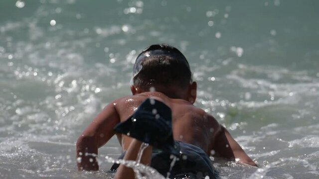  active little boy in diving mask and fins splashing and swimming in blue water sea during summer leisure vacation travel activity