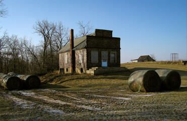 A boarded up country store in Pure Air, Missouri surrounded by hay bales with a barn in the background. 2007