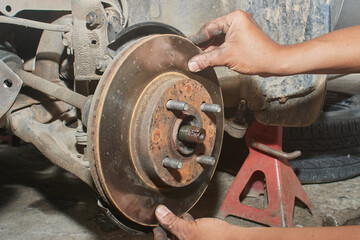 Car Mechanic Assemble Disk Brake to Front Car Wheel Hub in Car Repair Shop