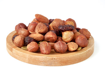 Hazelnut and almond kernels, raw pumpkin seeds and raisins on bamboo serving plate. Nut mix isolated on white