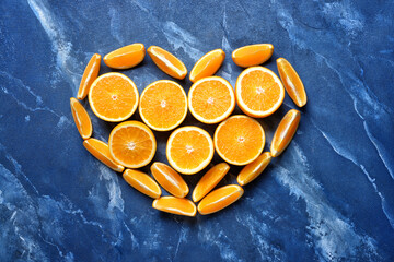 Heart made of cut oranges on color background