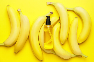 Bottle of essential oil and fresh bananas on color background