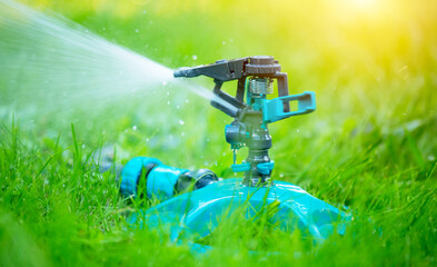 Sprinkler head watering green grass lawn. Gardening concept. Smart garden activated with full...