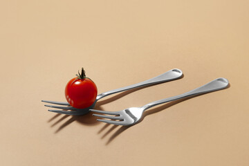 Tomato and forks on color background