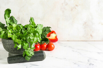 Mortar with herbs and pestle on light background