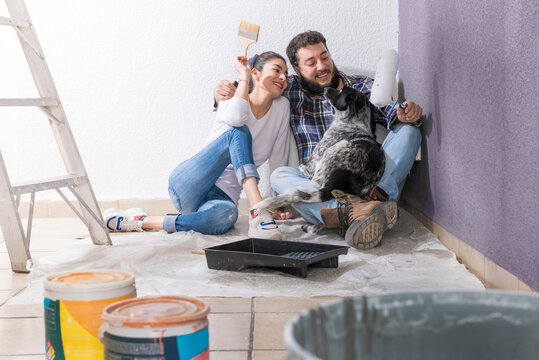 Couple opening their new house, young couple painting their new house in the company of their pet, they are happy, one day as a couple opening their house