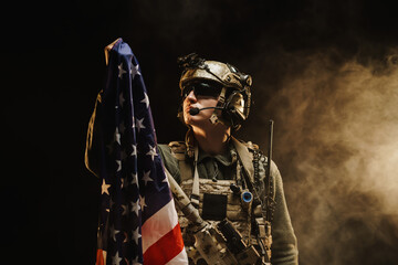 Special forces soldier holding US national flag in the dark