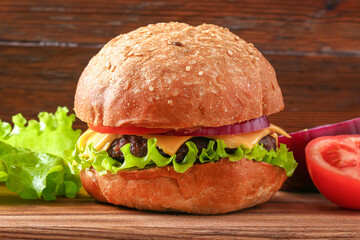 Homemade hamburger with cutlet, salad, onion, tomato and cheese. Cheeseburger, burger. Close-up of home made burgers