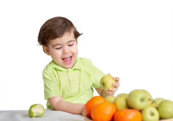 Fototapeta premium portrait of a little smiling cheerful boy taking an apple from a fruit plate