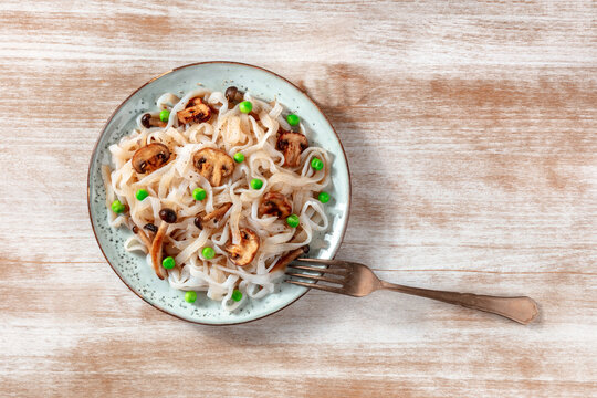 Vegan konjac pasta with mushrooms and green peas, shot from the top