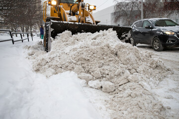 Snow removal in the city with a tractor or an excavator. Dirty snow.