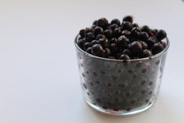 eating blueberry or currant berries in a glass glass on a white light background with a place to text the view from the side