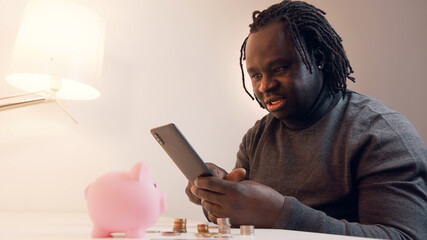 Fototapeta na wymiar Online shopping, Young african american black man using smartphone for online shopping and paying with credit card. High quality photo