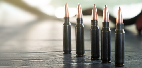Carbine or rifle cartridges standing in a row on the table. A large number of cases. Background of...