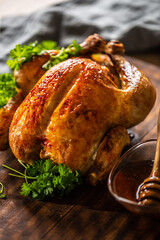 Whole baked chicken with crusty skin glazed with honey on top and parsley on the side