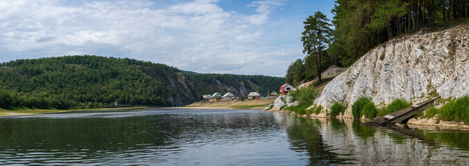 Summer still panoramic landscape with lake, shagged hill and small village in distance. Quiet and...