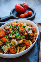 cooking tasty comfort food - italian fusilli pasta baked with meat sauce, cherry tomatoes and cheese