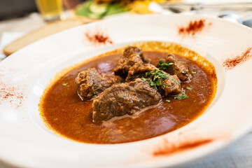 Beef stew with large chunks of meat served in a white plate