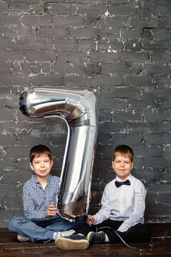 photo session with a ball 7 years old. Silver ballon with number 7. Boys at a photoset in the studio. 2 boys are smiling. Brothers take pictures together