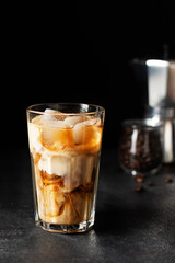 Iced coffee in a tall glass on black background.
