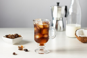 A glass of iced coffee on white wooden table.