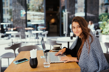 Portrait of female student using net-book while sitting in cafe