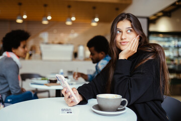 Female student using smartphone while sitting in cafe