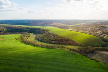 Fototapeta na wymiar Aerial view of beautiful countryside with green rolling field in golden hour before sunset