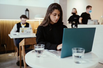 Portrait of female student using net-book while sitting in cafe