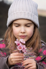 Close up portrait of a cute little girl with closed eyes, holding cherry blossom