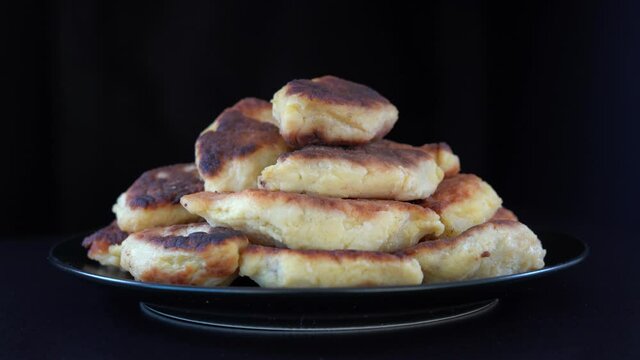 Potato cakes, ukrainian name potato zrazy, stuffed mushrooms or meat or cheese with herbs cream are fried in vegetable oil on black background, close up, rotates. Traditional Ukrainian cuisine