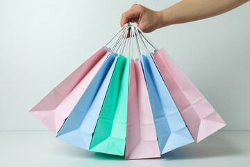 Female hand hold colorful paper bags on white background