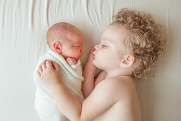 Newborn baby sleeping next to his older brother little boy