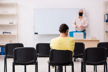 Young male student and experienced teacher in pandemic concept