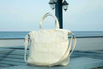 Stylish eco bag outdoor on wooden counter against sea horizon
